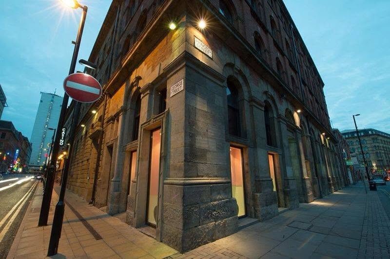 The stone building at 83 Princess Street, lit up at dusk