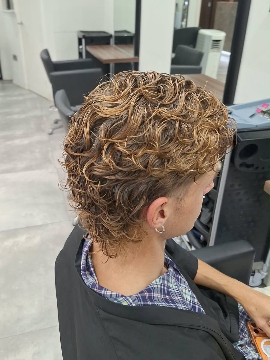 A men’s perm with tight golden-tipped curls