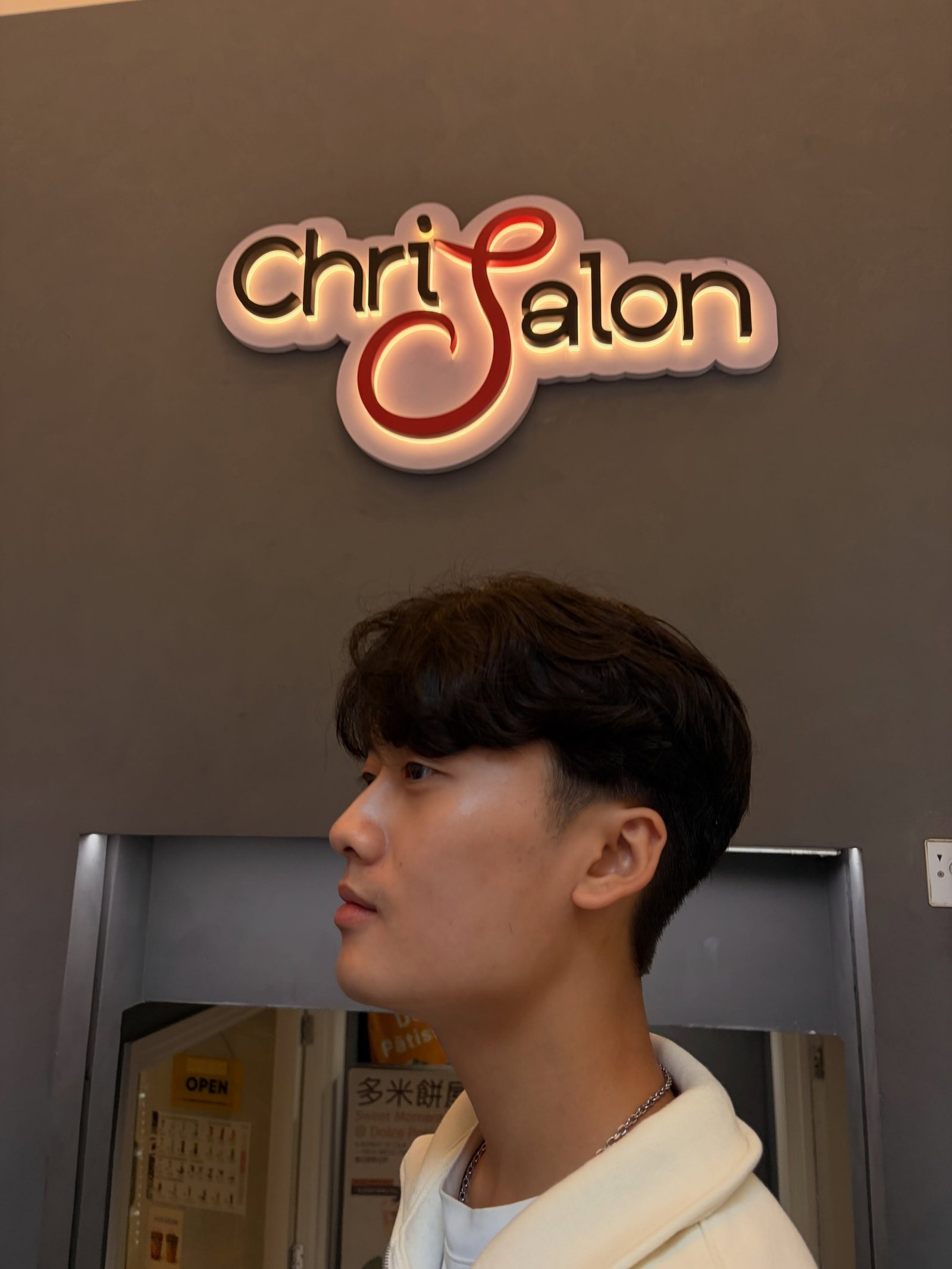 A client under the lit ChriSalon sign