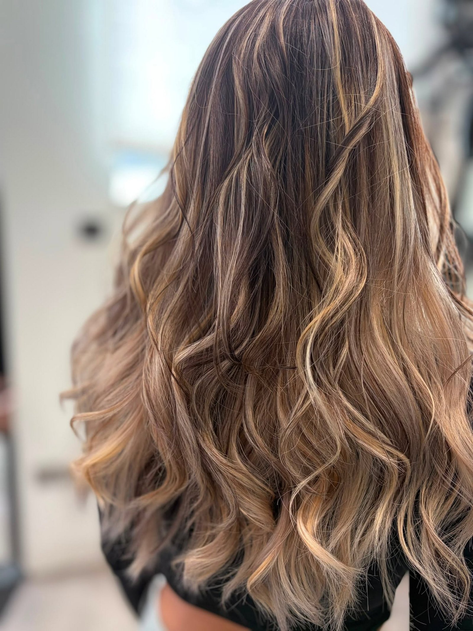 Hand-painted balayage in honey and beige tones, styled in loose waves