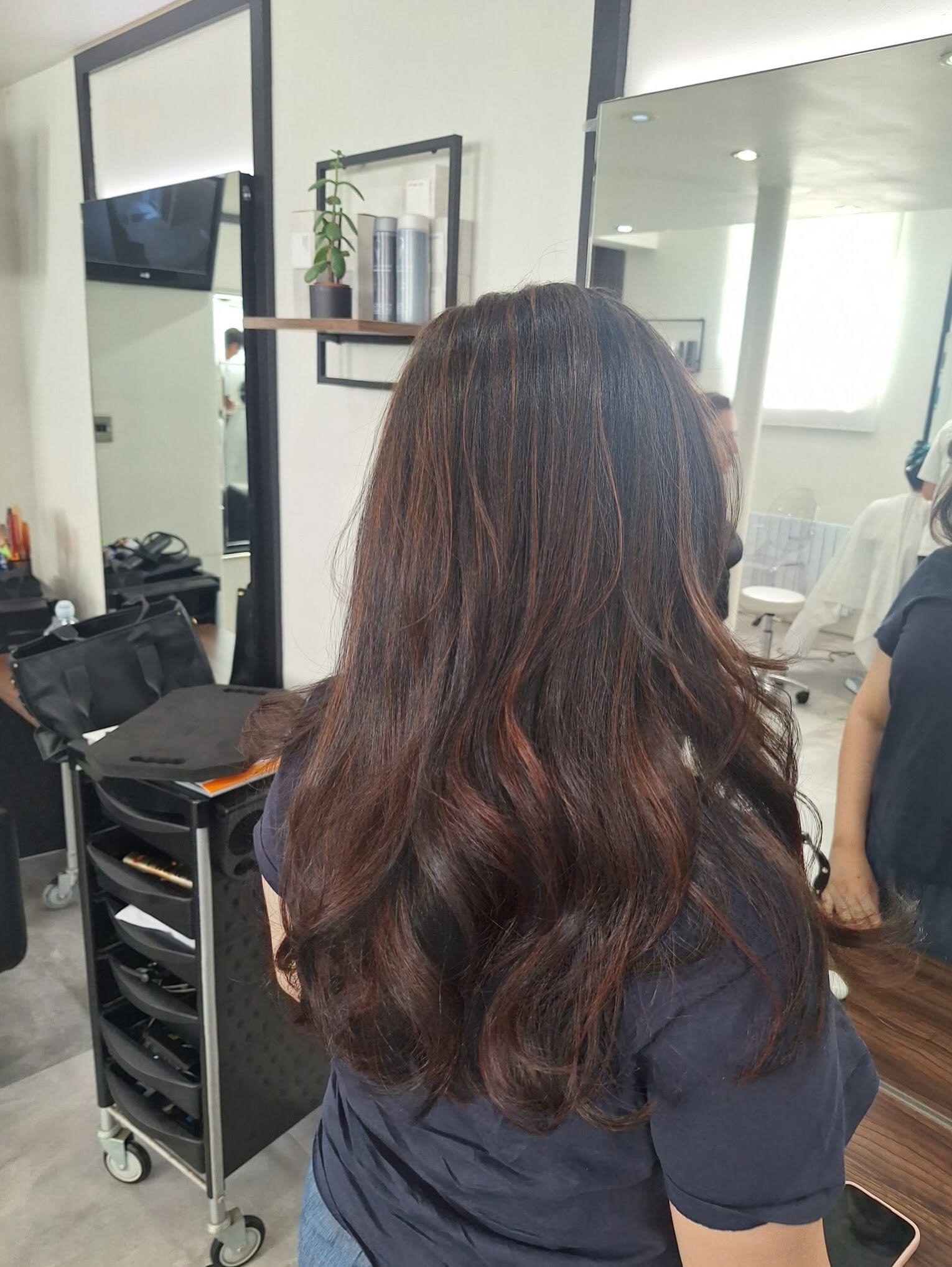 Long dark hair with copper tones, finished with soft waves, inside the salon